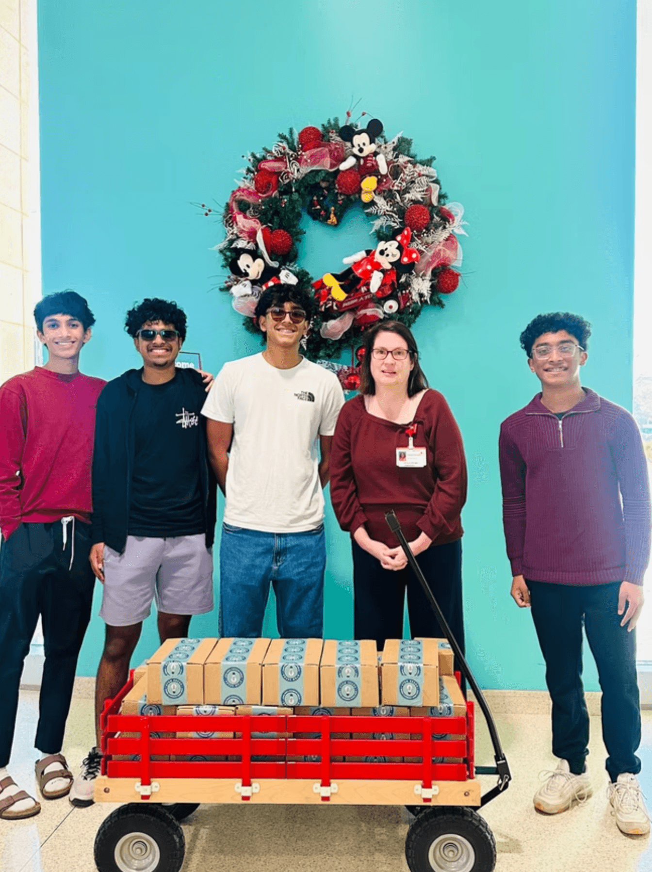 STEMSeeds members and a hospital staff member standing with a wagon of STEM kits