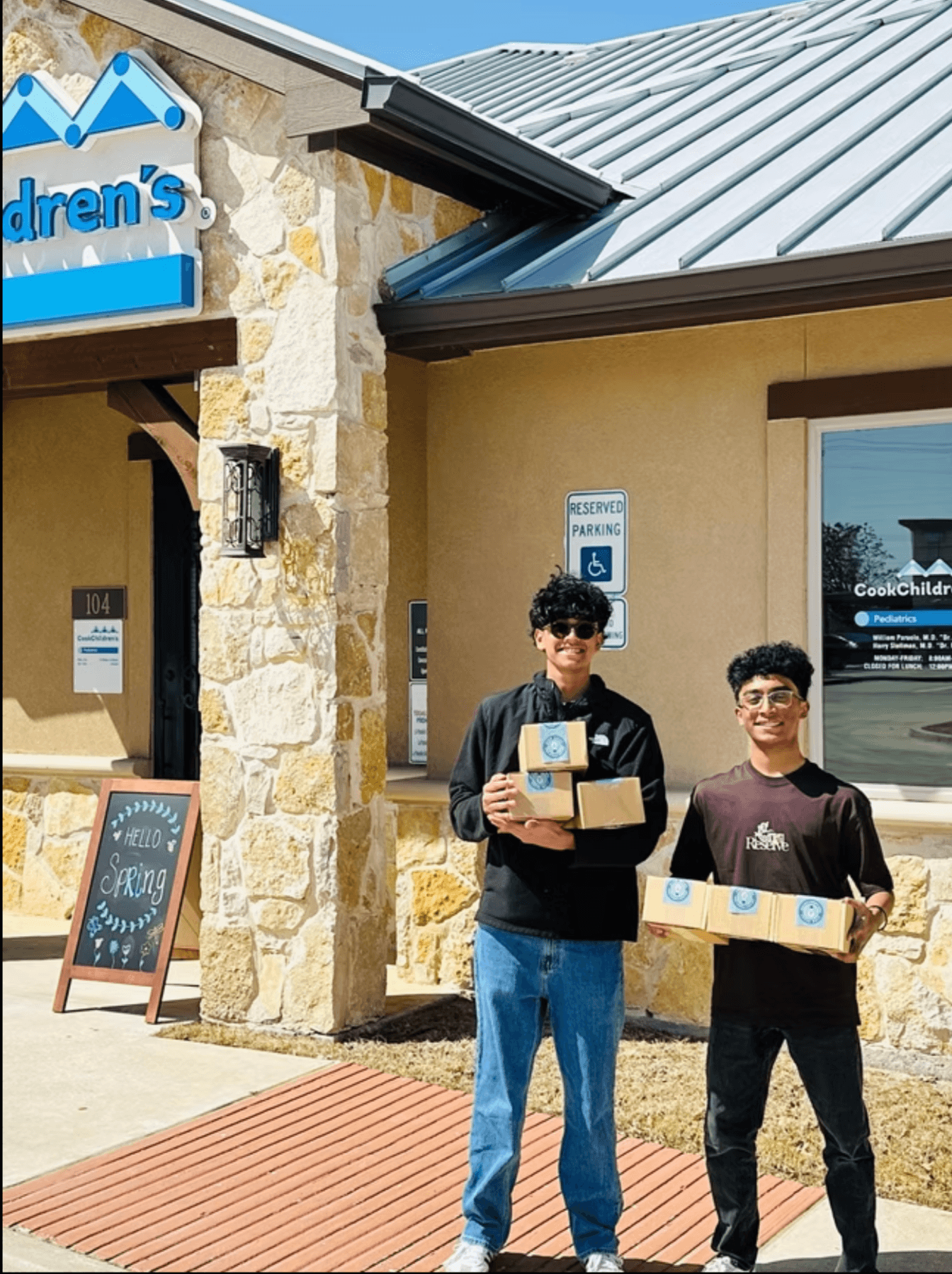 Two STEMSeeds members holding kits outside a Cook Children's clinic